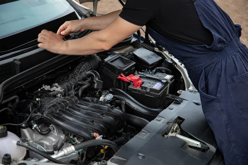Mecánico dando mantenimiento al motor bajo el cofre