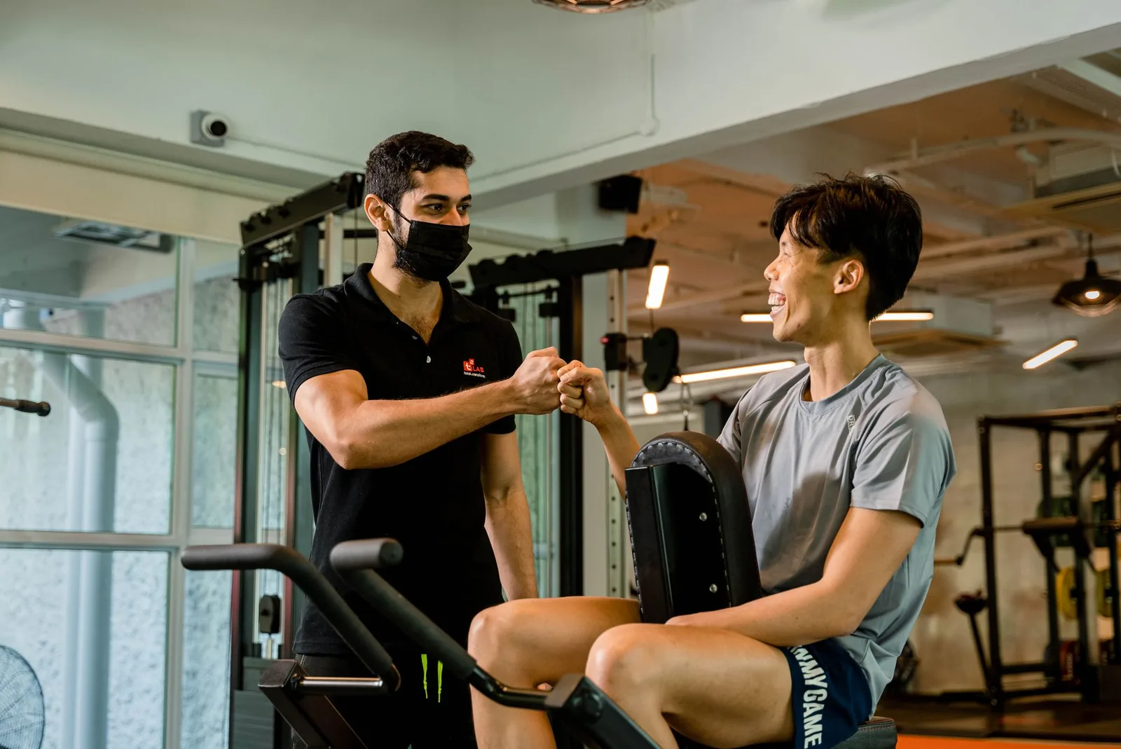 Personal trainer fist-bumping a smiling client in a gym