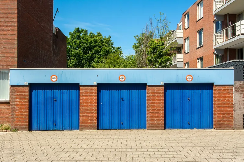 Three blue garage doors in a brick building