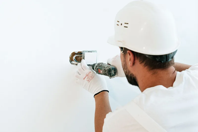 Técnico con casco arreglando un interruptor en la pared