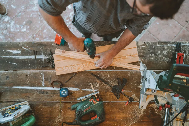 Artesano taladrando tablones de madera en un taller