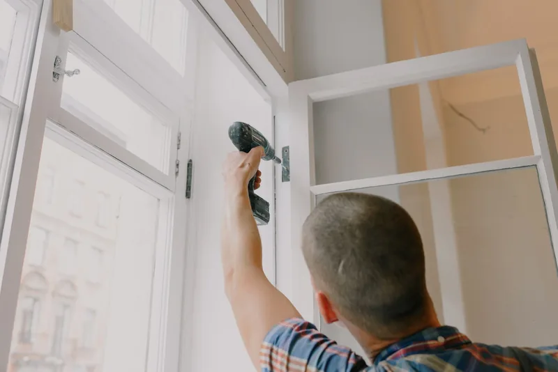 Hombre de mantenimiento instalando un marco de ventana con taladro inalámbrico