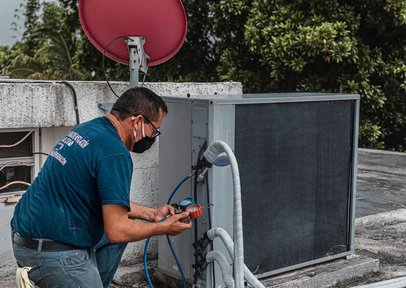 Técnico revisando los manómetros de refrigerante de un aire acondicionado
