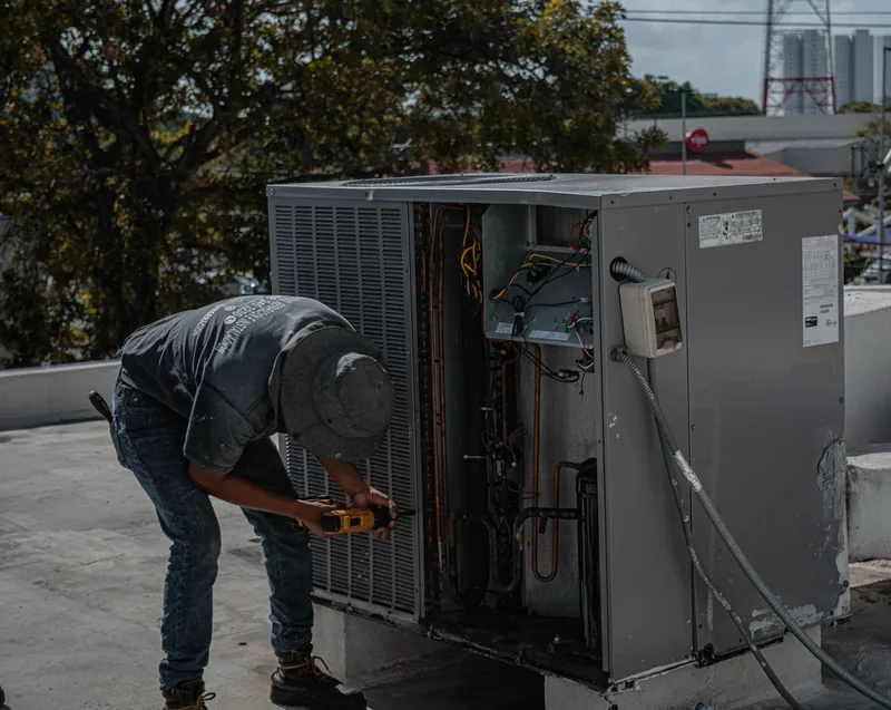 Técnico trabajando en la carcasa de un aire acondicionado con taladro