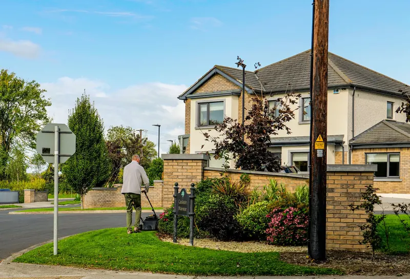 Man mowing the lawn in front of a suburban home