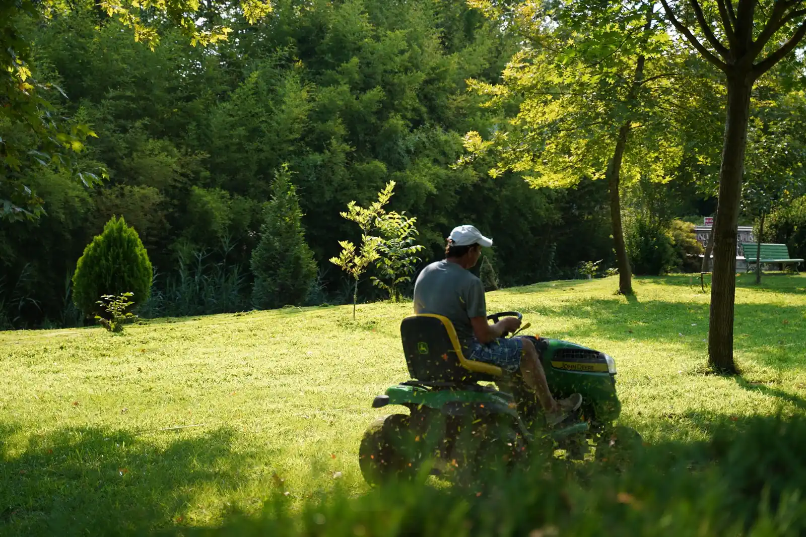 Landscaper mowing a green lawn on a ride-on mower