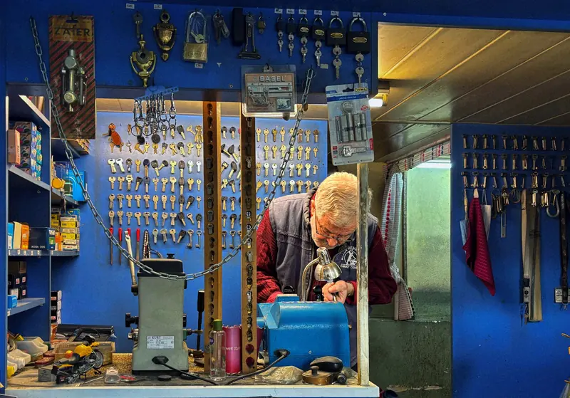 Locksmith cutting a key in a workshop full of keys