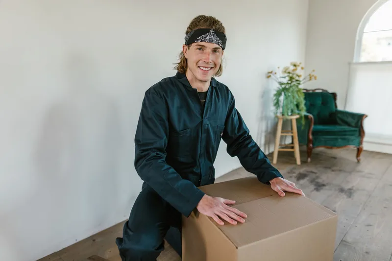 Smiling mover packing a cardboard box