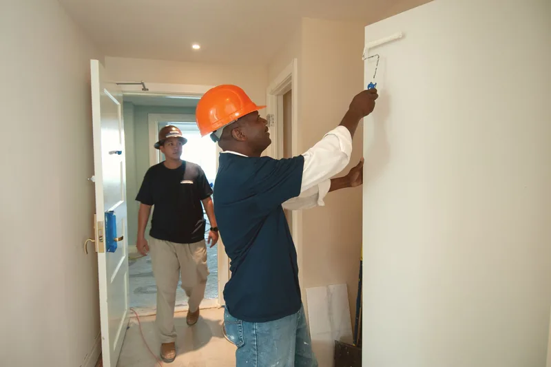 Two painters rolling an interior wall